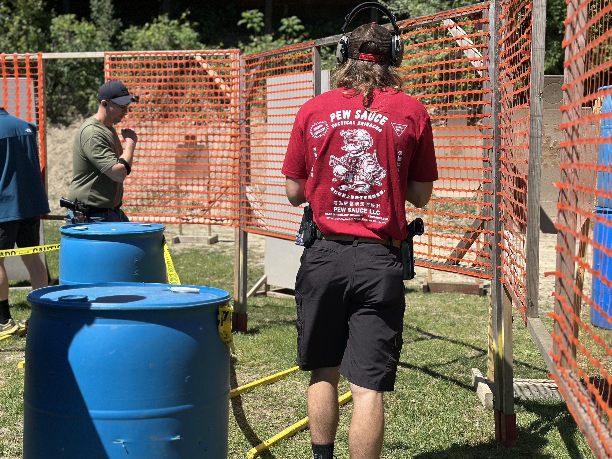 Shooter at a competition stage wearing a Pew Sauce branded shirt